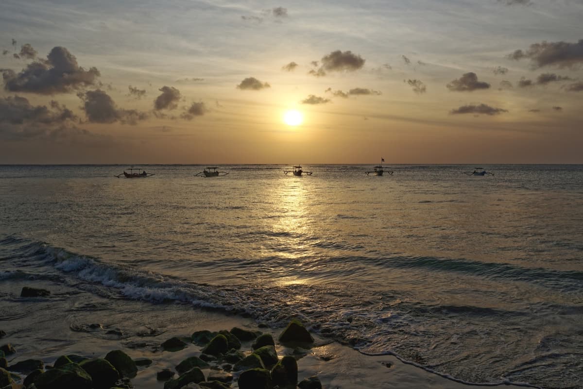 Sunset at Kuta Beach | Bali | Go Bali Visa Agency Orange sunset over Kuta Beach with palm silhouettes on Bali's southwest coast